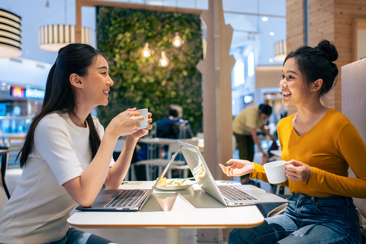 Asain beautiful woman working and eating food together in restaurant. Attractive young woman use laptop feeling happy and relax, having fun hangout indoors enjoy meeting reunion in cafe cafetaria.