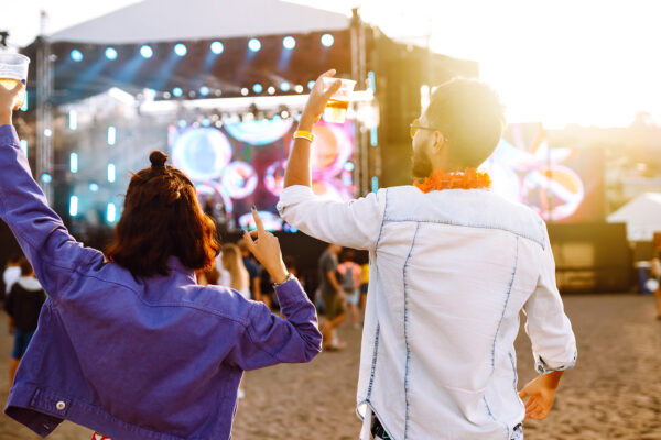 Group of friends with beer dancing and having fun at music festival together. Summer Beach party.