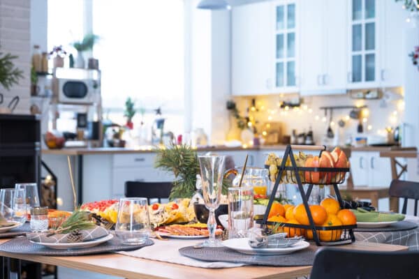 Festive interior of house is decorated for Christmas and New Year in loft style with black stove, fireplace, Christmas tree. Warm studio room with set table, burning wood, cozy and heating of home